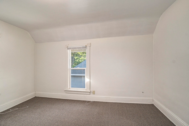 empty room featuring vaulted ceiling and carpet flooring