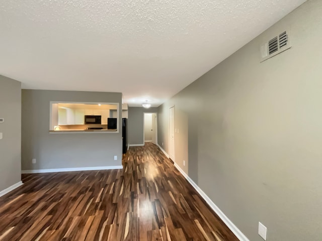 unfurnished living room with a textured ceiling and dark wood-type flooring