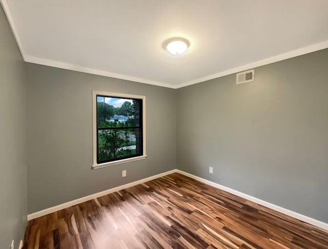 empty room featuring hardwood / wood-style flooring and ornamental molding