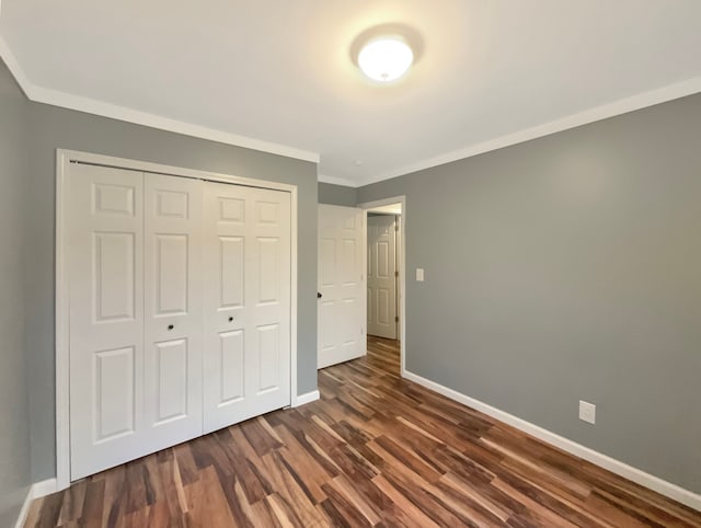 unfurnished bedroom featuring dark hardwood / wood-style floors, crown molding, and a closet