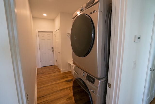 laundry area featuring hardwood / wood-style floors and stacked washing maching and dryer