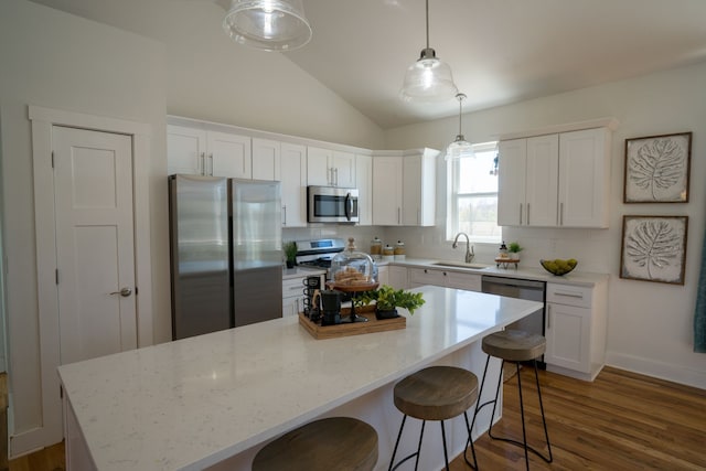 kitchen with pendant lighting, white cabinets, sink, appliances with stainless steel finishes, and a kitchen island