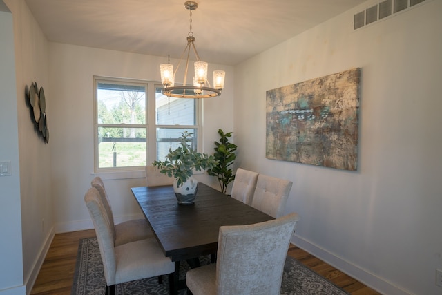 dining room with dark hardwood / wood-style floors and an inviting chandelier