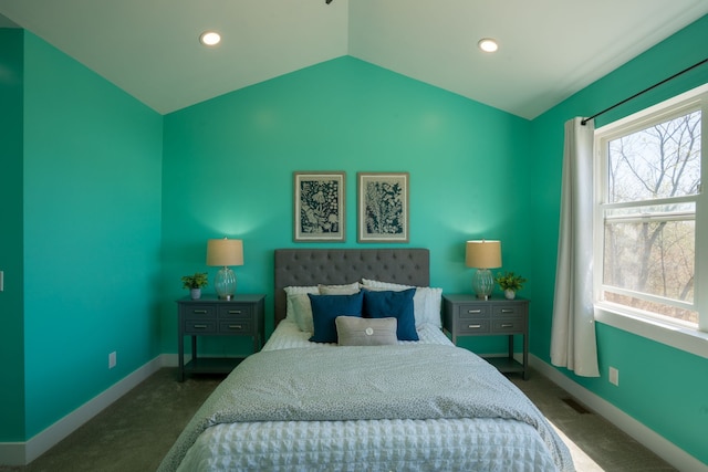 bedroom featuring dark colored carpet, vaulted ceiling, and multiple windows