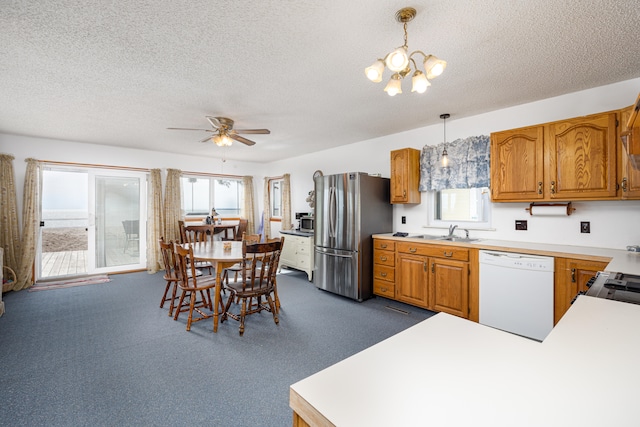 kitchen featuring a wealth of natural light, stainless steel fridge, white dishwasher, and decorative light fixtures