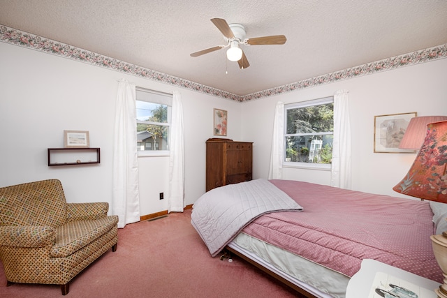 bedroom featuring multiple windows, ceiling fan, carpet, and a textured ceiling