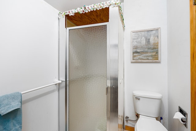 bathroom with toilet and a shower with door