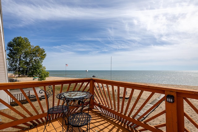 wooden terrace featuring a beach view and a water view
