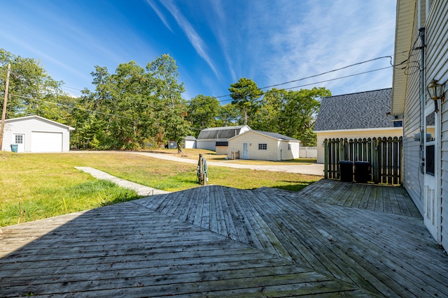 wooden terrace featuring a lawn and an outbuilding