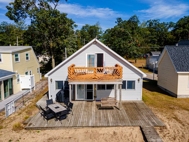 rear view of house featuring a balcony and a wooden deck