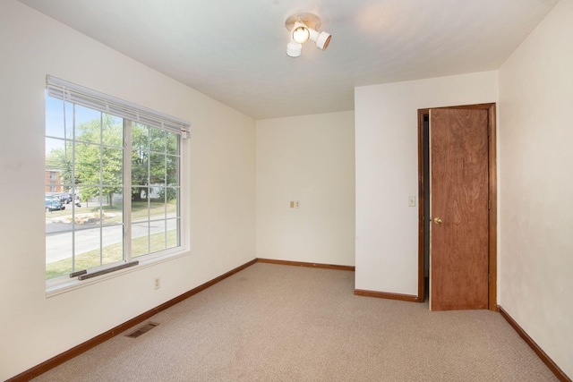 empty room featuring a wealth of natural light and light carpet