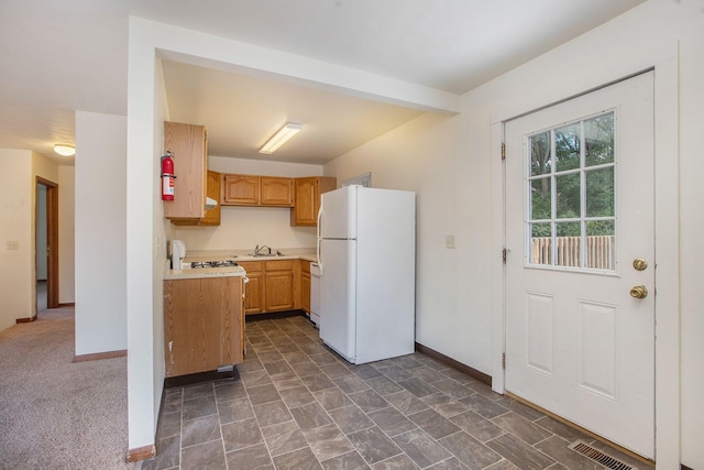 kitchen with dark colored carpet, white appliances, sink, and light brown cabinetry