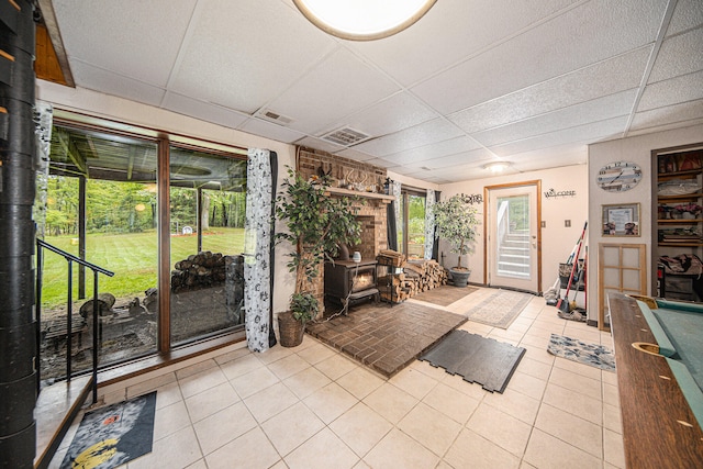 interior space with a wood stove, a drop ceiling, and billiards