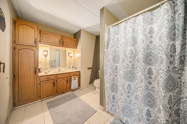 bathroom featuring a paneled ceiling, tile patterned flooring, and toilet