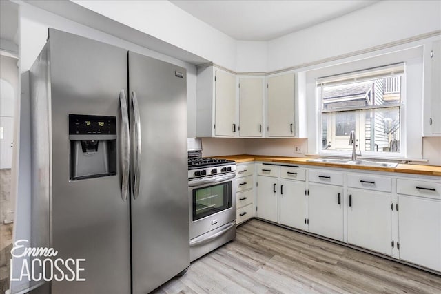318 Diamond Ave SE, Grand Rapids, MI 49506 - kitchen featuring appliances with stainless steel finishes, a sink, light wood-style flooring, butcher block countertops, and white cabinetry