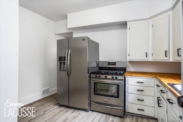318 Diamond Ave SE, Grand Rapids, MI 49506 - kitchen with appliances with stainless steel finishes, butcher block counters, light wood finished floors, white cabinetry, and baseboards
