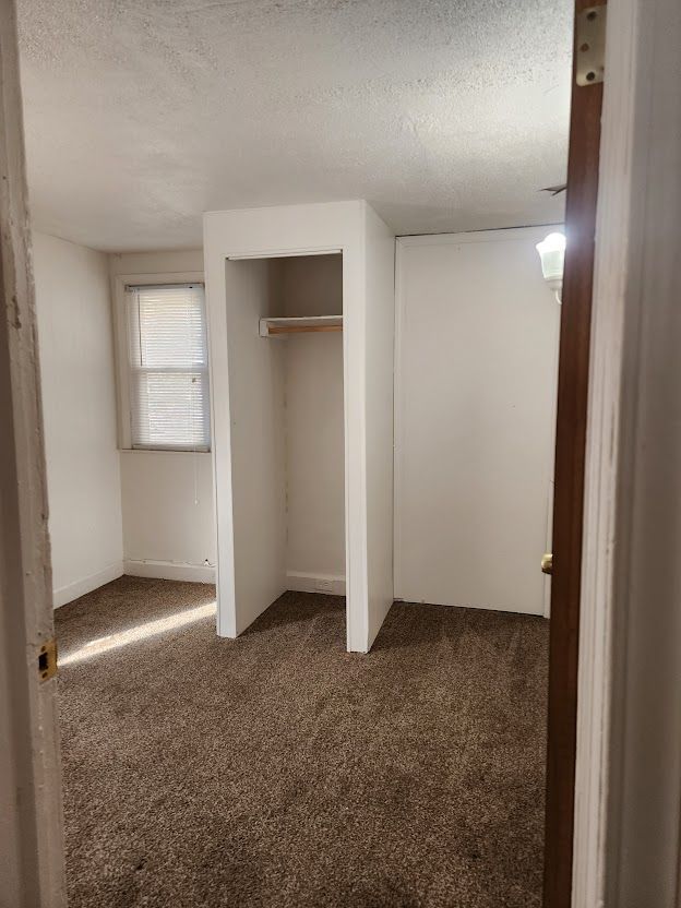 unfurnished bedroom featuring dark colored carpet and a textured ceiling