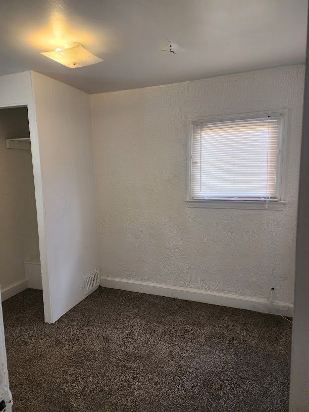 unfurnished bedroom featuring dark carpet and a closet