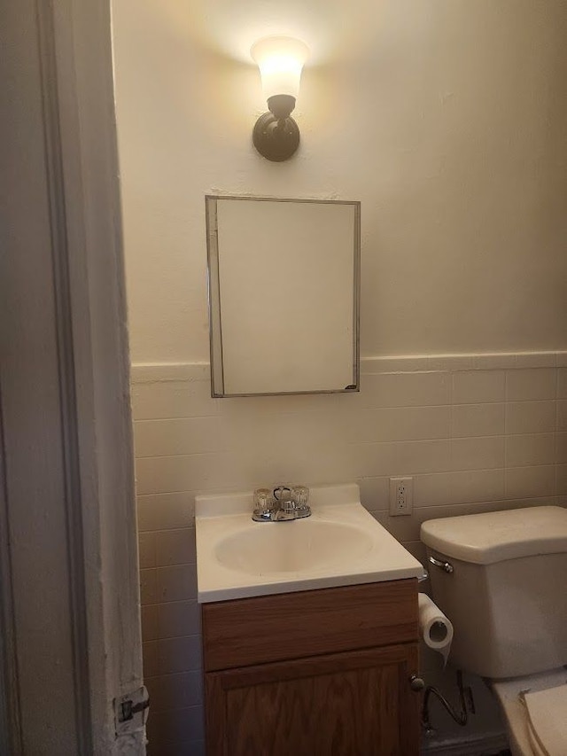 bathroom featuring vanity, tile walls, and toilet