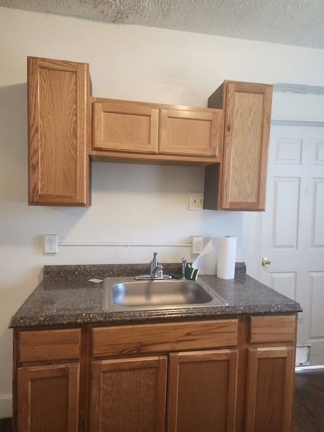 kitchen with dark stone countertops, sink, and a textured ceiling