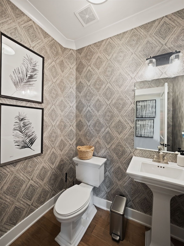 bathroom with hardwood / wood-style flooring, toilet, and ornamental molding