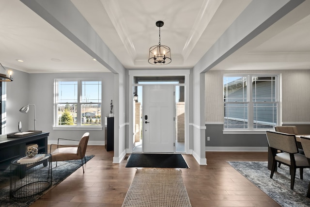 foyer entrance with dark hardwood / wood-style flooring, a wealth of natural light, and an inviting chandelier