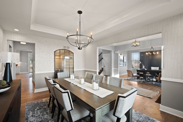 dining room with a chandelier, hardwood / wood-style flooring, and a raised ceiling