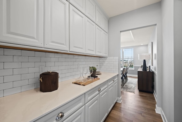 kitchen featuring dark hardwood / wood-style floors, white cabinetry, and backsplash