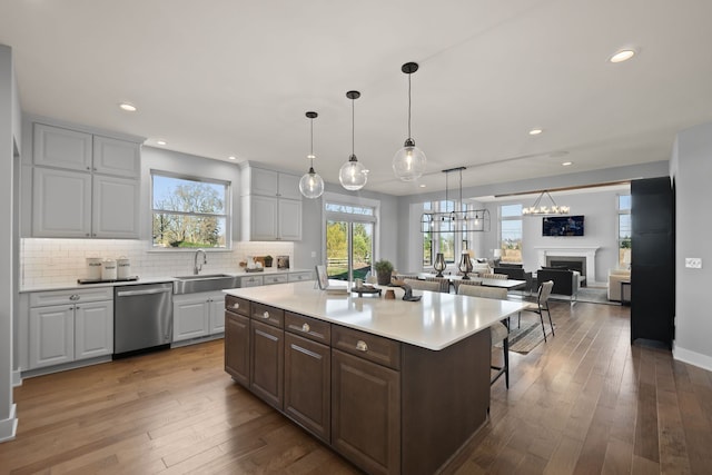 kitchen with white cabinets, hardwood / wood-style flooring, stainless steel dishwasher, and a kitchen island