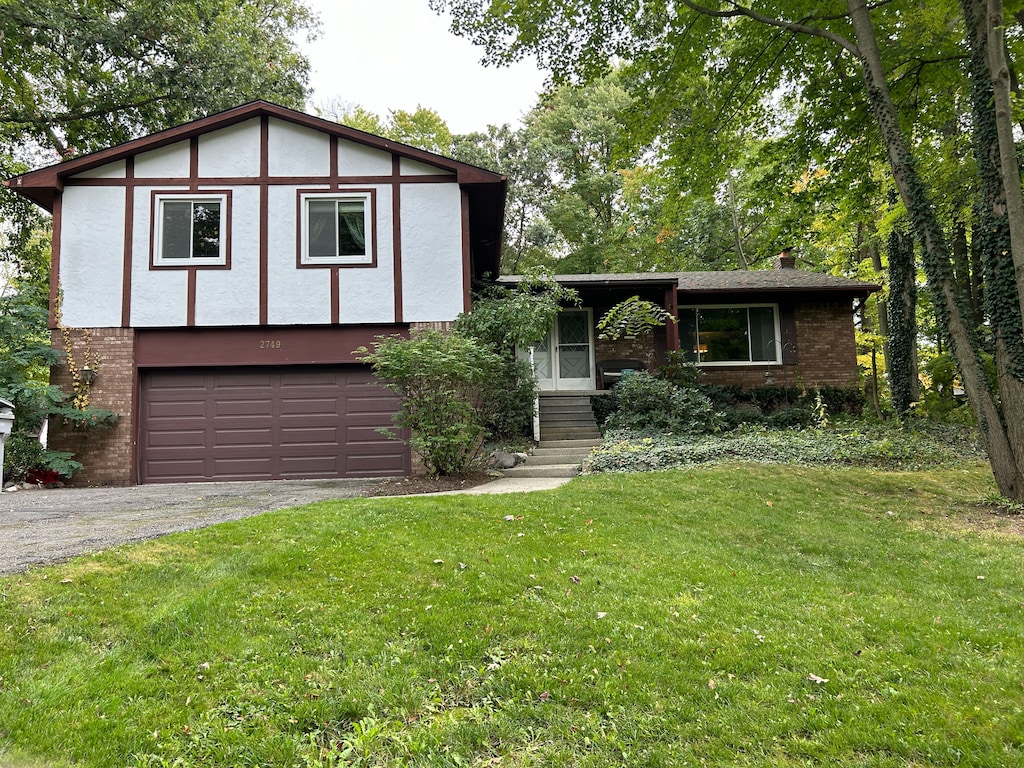 english style home featuring a garage and a front lawn