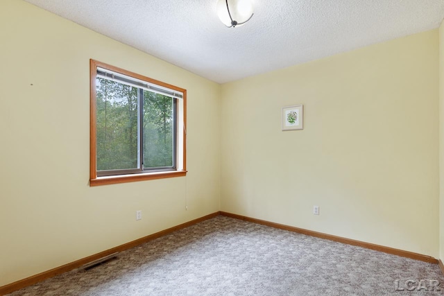 carpeted empty room featuring a textured ceiling