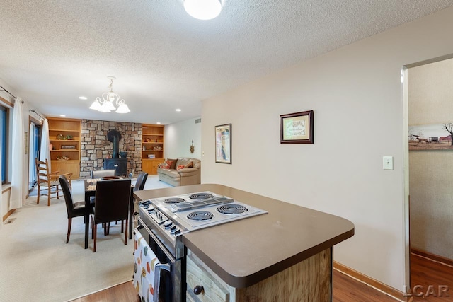 kitchen with a textured ceiling, electric range, hardwood / wood-style floors, and built in features