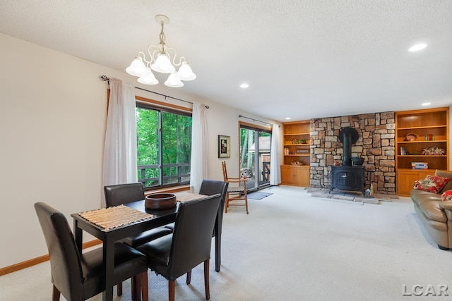 dining space featuring light colored carpet, a wood stove, a textured ceiling, and an inviting chandelier