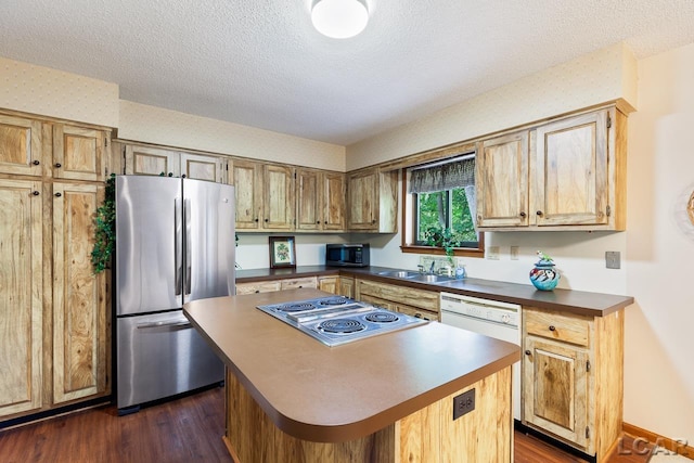 kitchen with appliances with stainless steel finishes, a textured ceiling, a kitchen island, and dark wood-type flooring