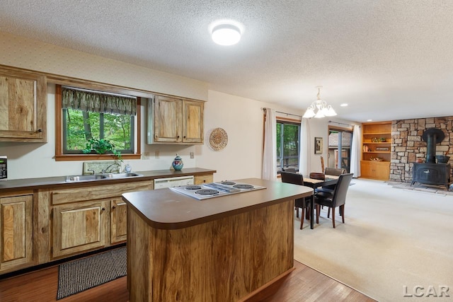 kitchen with pendant lighting, sink, light hardwood / wood-style flooring, a kitchen island, and a chandelier