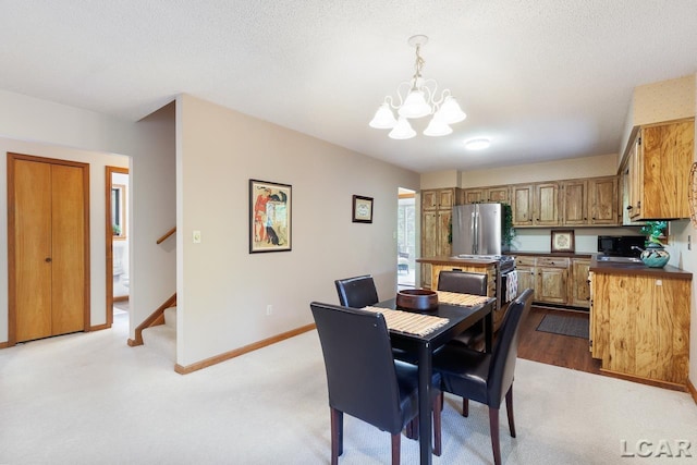 dining room featuring a chandelier, a textured ceiling, and light wood-type flooring