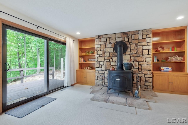 carpeted living room with built in shelves, a healthy amount of sunlight, and a wood stove