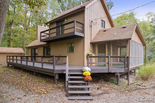 back of house featuring a sunroom, a balcony, and a deck