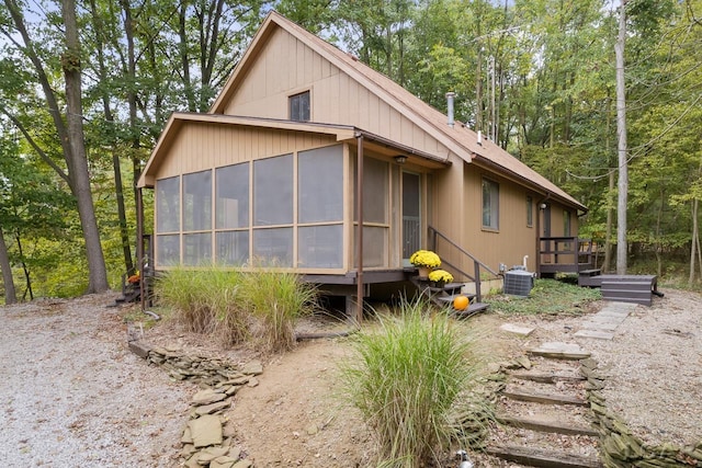 view of side of property featuring a sunroom, a wooden deck, and central AC