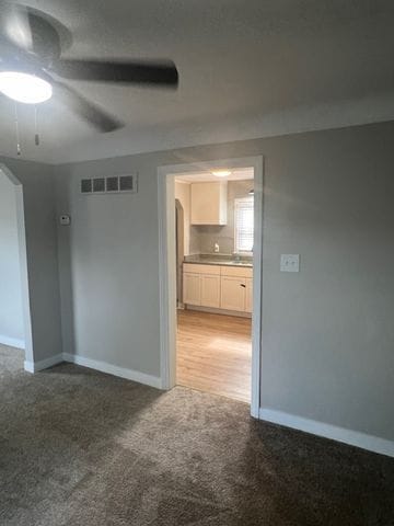 carpeted empty room featuring ceiling fan