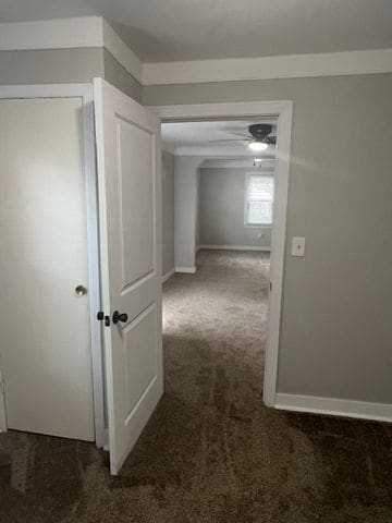 hall featuring dark colored carpet