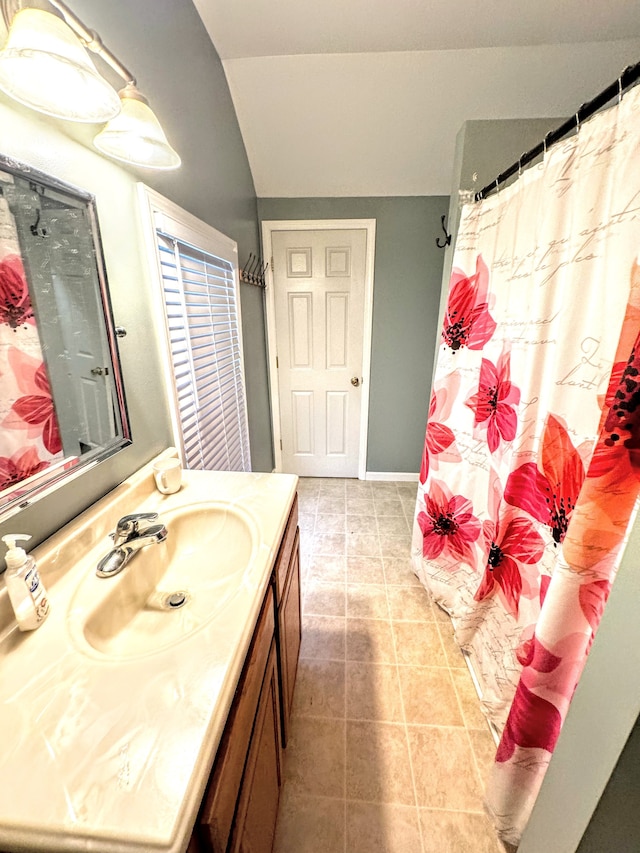 bathroom with tile patterned flooring, vanity, and vaulted ceiling