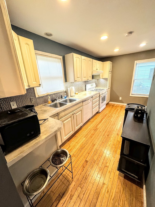 kitchen with backsplash, sink, light hardwood / wood-style floors, and white appliances