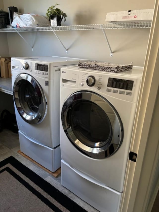 washroom with washing machine and clothes dryer and hardwood / wood-style floors