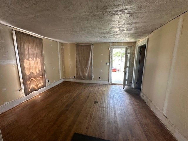 unfurnished room with a textured ceiling and dark hardwood / wood-style floors