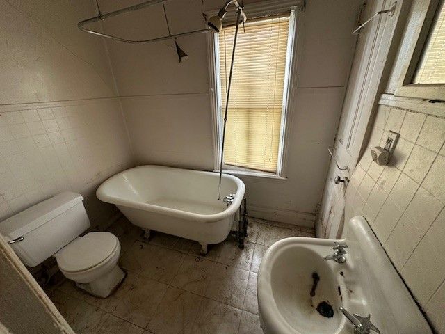 4238 Bangor St, Detroit, MI 48210 - full bathroom featuring tile walls, a soaking tub, toilet, healthy amount of natural light, and tile patterned flooring