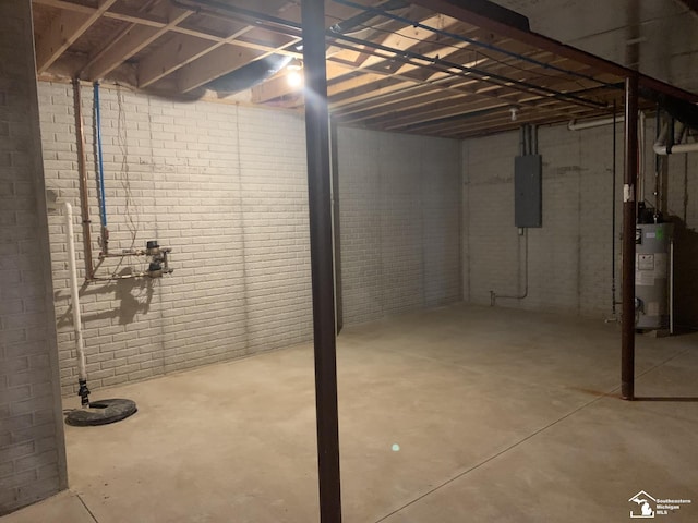 basement featuring electric panel, brick wall, and gas water heater