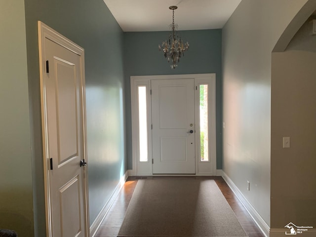 entryway featuring dark wood-type flooring and a chandelier