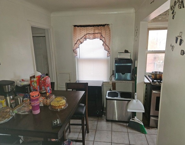 dining room with light tile patterned floors, ornamental molding, and a healthy amount of sunlight