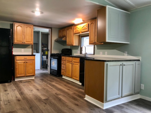 kitchen with sink, water heater, dark hardwood / wood-style floors, washer / clothes dryer, and black appliances